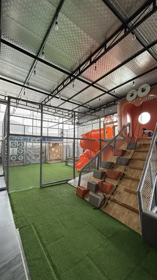 The caged football and basketball court, with the tube slide and padded stairs beside it — Kids Coffee — an indoor play room with a cafe, Da Lat