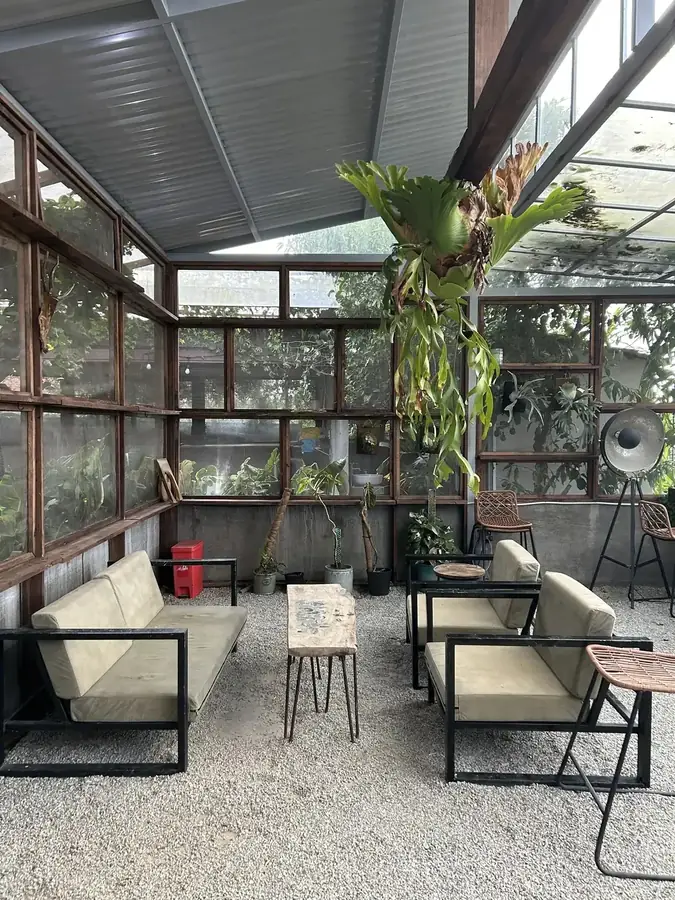 The glass-walled room with armchairs and gravel underfoot — LSD Coffee Mèo — a cat cafe with a valley view, Da Lat