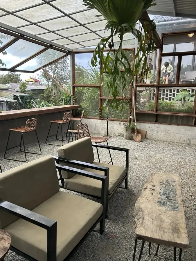 The terrace under a translucent roof: low armchairs and a slab table — LSD Coffee Mèo — a cat cafe with a valley view, Da Lat