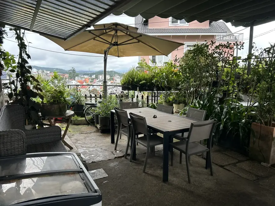 Tables on the terrace under the awning and umbrella, looking over the city — Moto Laurie — breakfasts and a vegan menu over the city, Da Lat