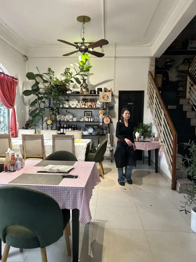 The lower room: checked tablecloths, green chairs and the stairs up — Moto Laurie — breakfasts and a vegan menu over the city, Da Lat