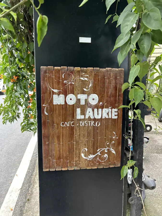 The wooden Moto Laurie Cafe & Bistro sign at the entrance — Moto Laurie — breakfasts and a vegan menu over the city, Da Lat