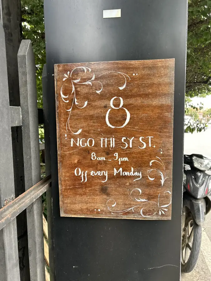 The board on the pillar: 8 Ngo Thi Sy St, 8am–9pm, closed Mondays — Moto Laurie — breakfasts and a vegan menu over the city, Da Lat