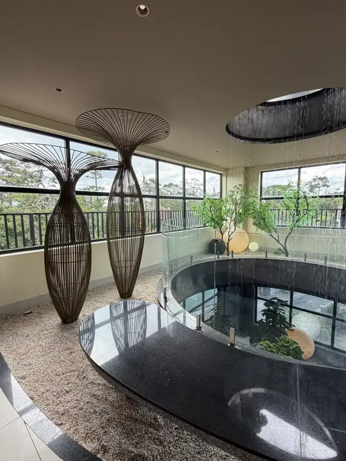 The dark oval indoor pool under woven lamps — Suoi May Onsen & Spa — Japanese baths looking into the pines, Da Lat