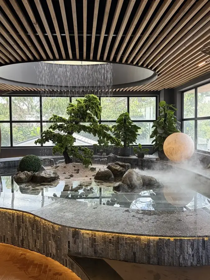 The main steaming pool under a round lamp, with the city in the windows — Suoi May Onsen & Spa — Japanese baths looking into the pines, Da Lat