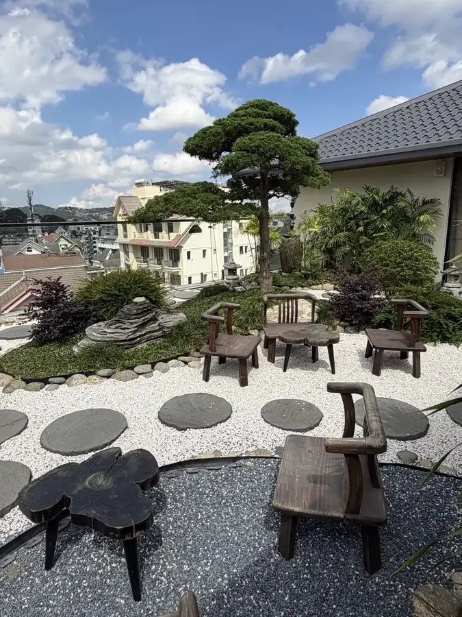 The rooftop Japanese garden: white gravel, clipped pines and benches — Suoi May Onsen & Spa — Japanese baths looking into the pines, Da Lat