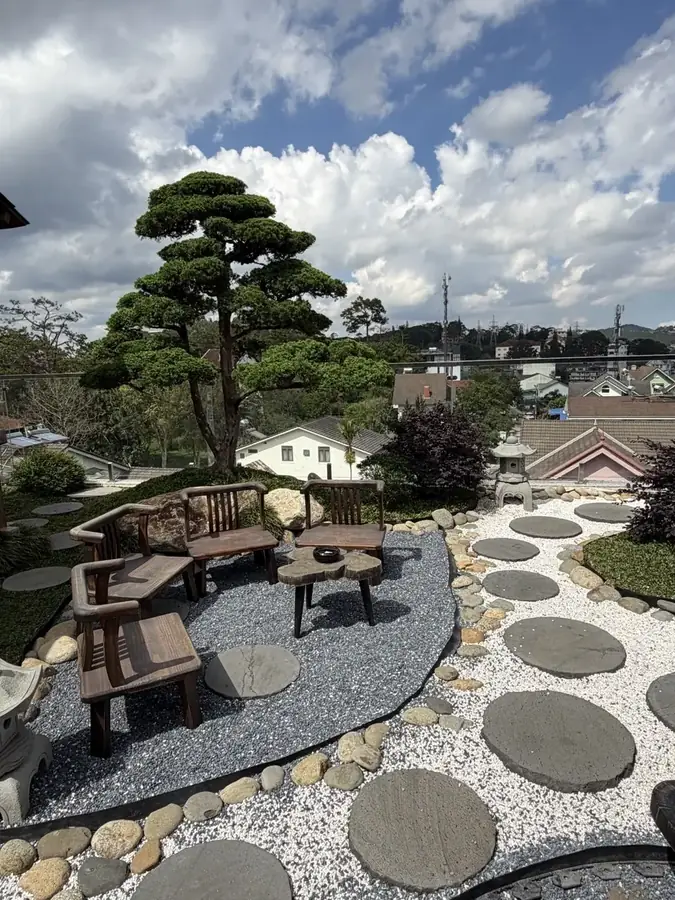 A path of round slabs across the garden, city blocks behind it — Suoi May Onsen & Spa — Japanese baths looking into the pines, Da Lat