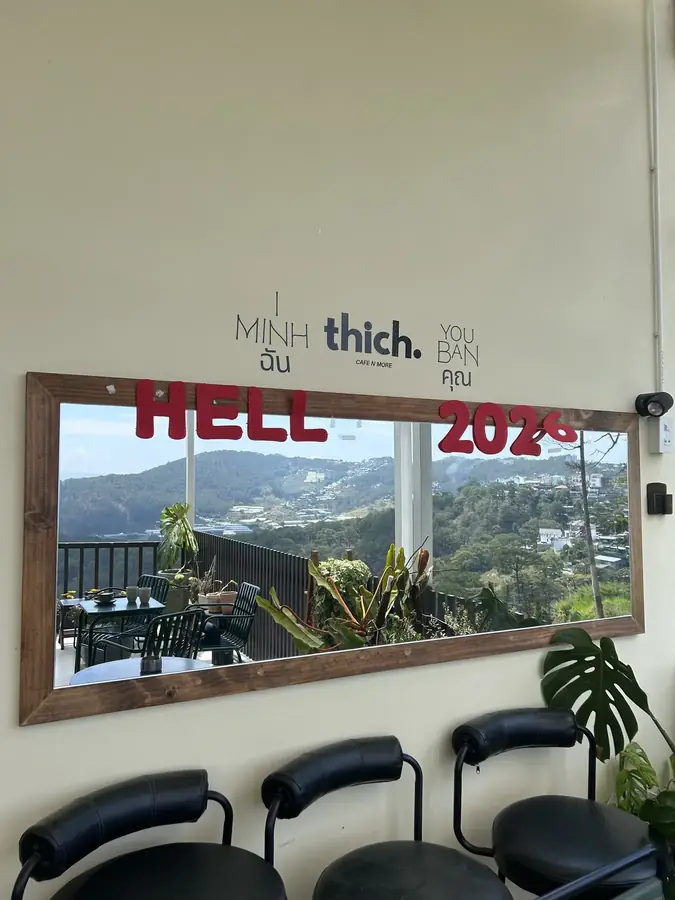 The full-height mirror: the hills reflected a second time — Thich Cafenmore coffee shop — a hill view without queueing for a table, Da Lat